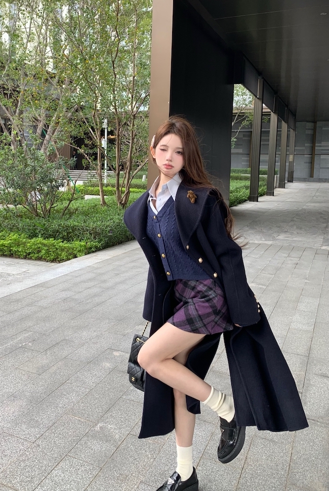 Real shot of mid-length woolen coat with large lapel + fake two-piece twist knitted top and plaid skirt