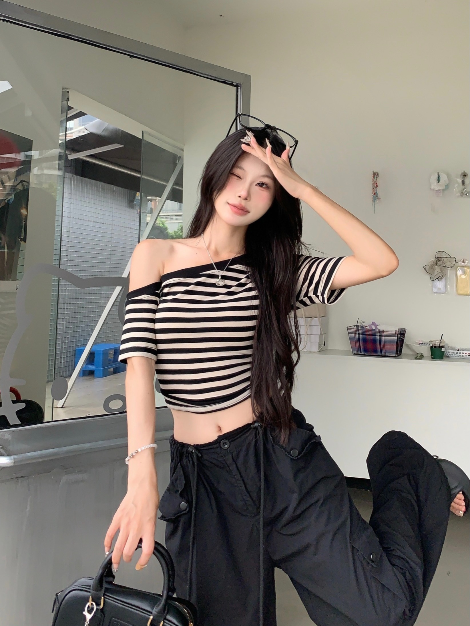 Real shot of slanted shoulder striped short-sleeved T-shirt for women in summer. Irregular, chic and beautiful off-shoulder tight cropped top.