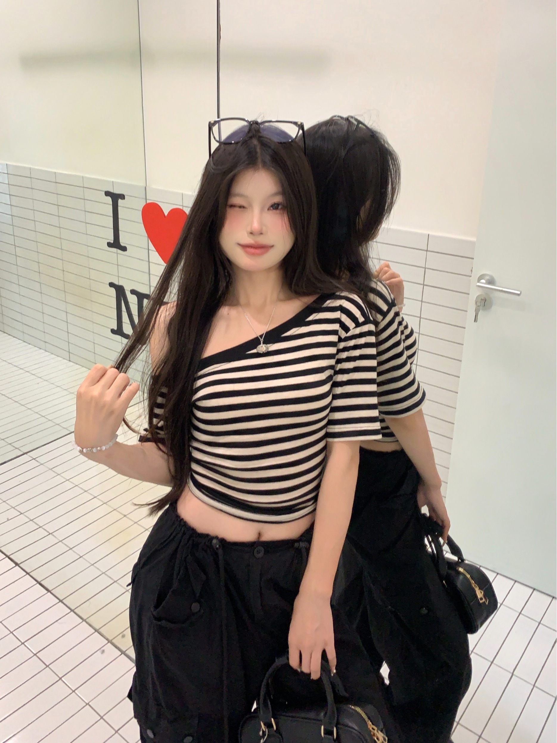 Real shot of slanted shoulder striped short-sleeved T-shirt for women in summer. Irregular, chic and beautiful off-shoulder tight cropped top.