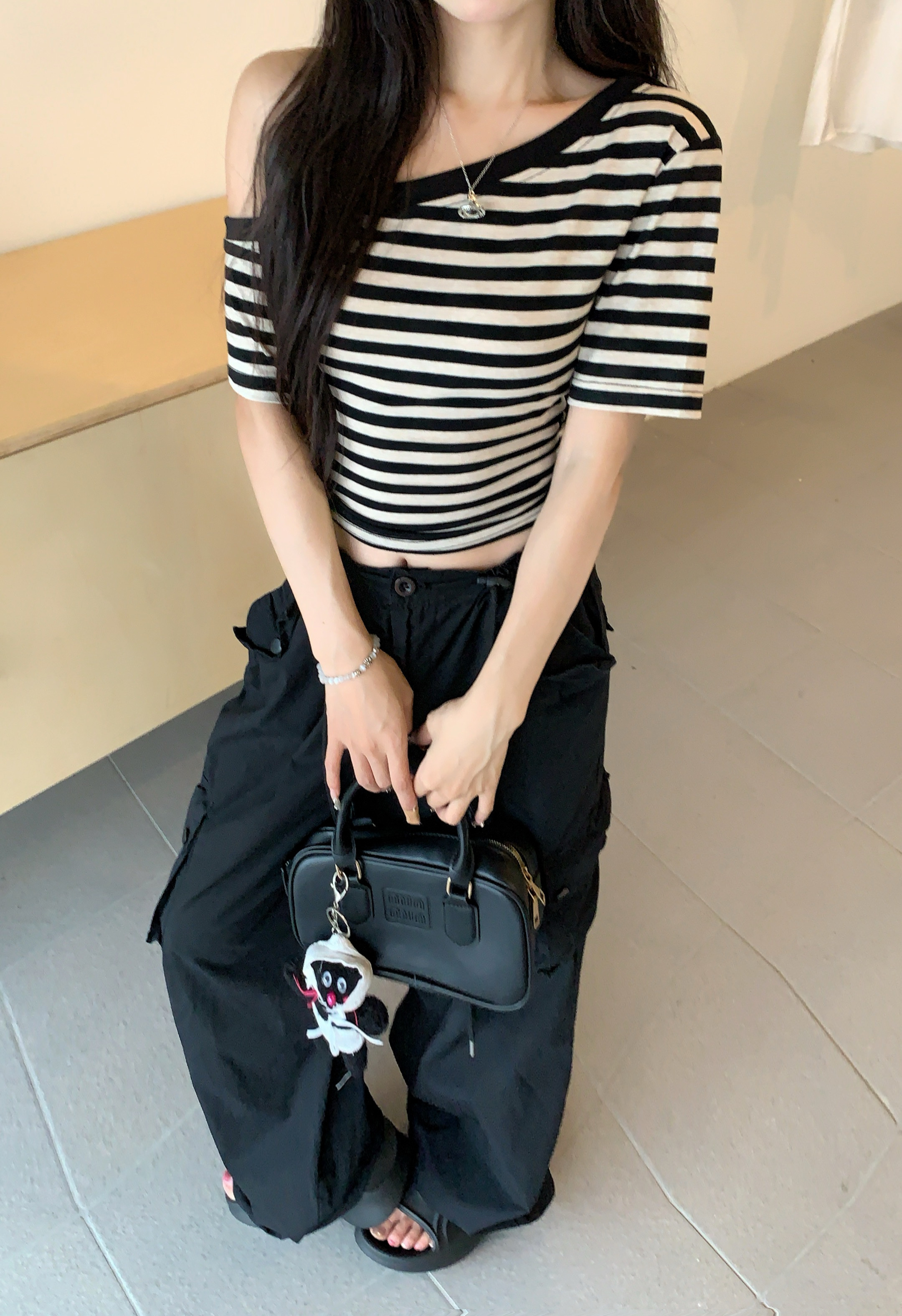 Real shot of slanted shoulder striped short-sleeved T-shirt for women in summer. Irregular, chic and beautiful off-shoulder tight cropped top.